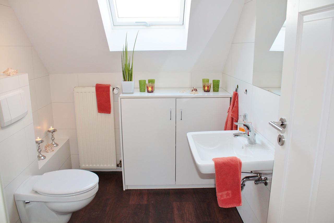 small white bathroom with hardwood floor and coral towels
