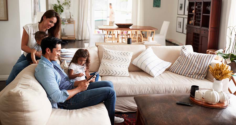family sitting in living room reading tablet on couch