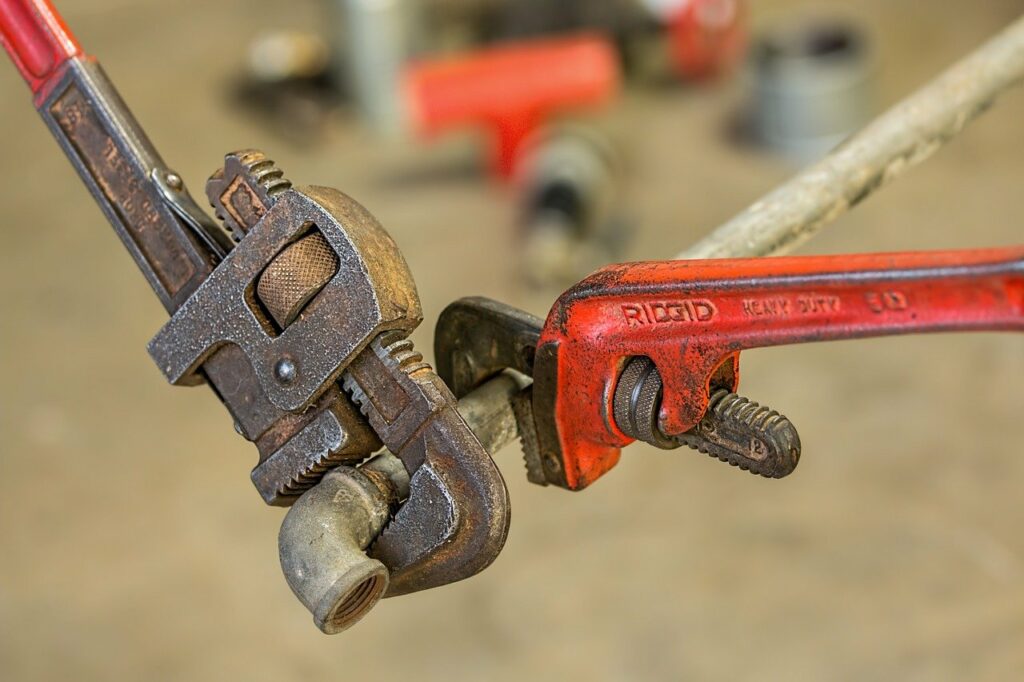 old red plumbing tools on dirty pipe