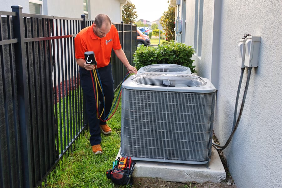 Mac 5 tech standing next to an air conditioning unit outside.