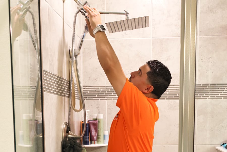 Mac 5 plumber replacing shower head with new head.