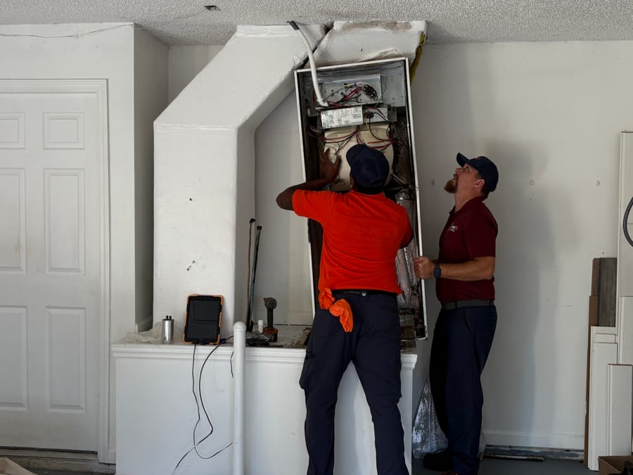 Two HVAC techs installing a new heater.