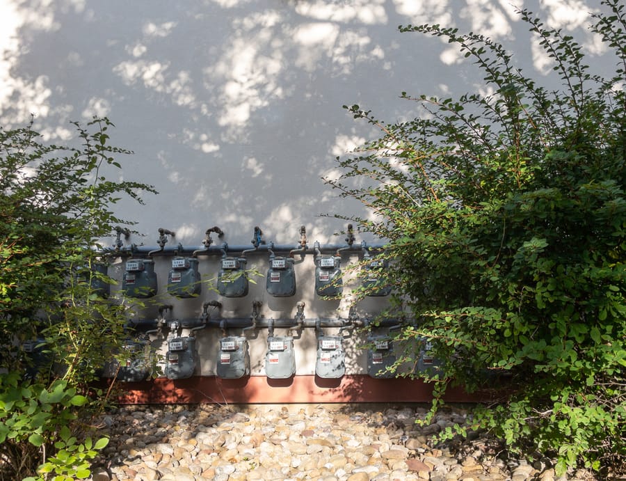 Gas meters measuring utility supply on exterior house wall.