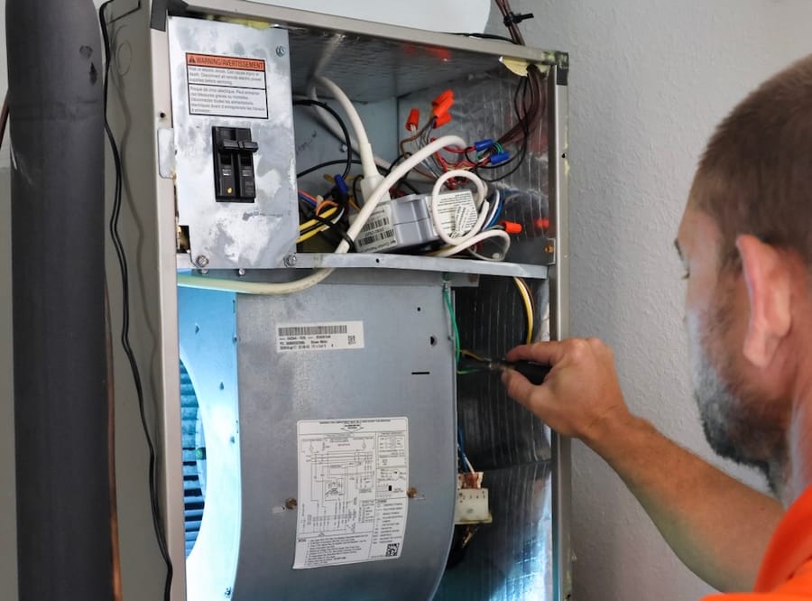 HVAC tech repairing open heating system.