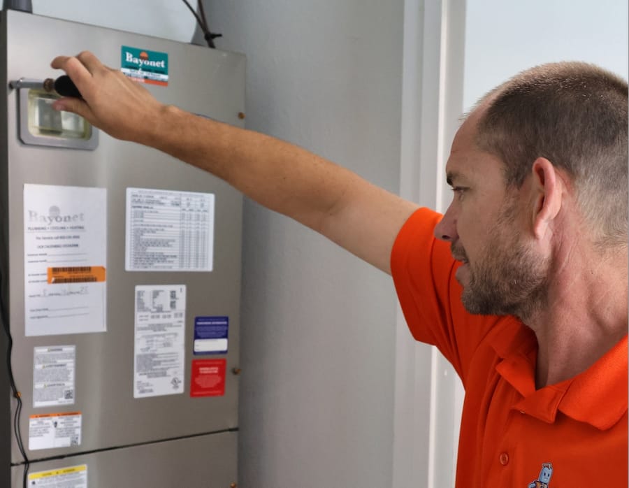 HVAC technician using screwdriver on furnace.