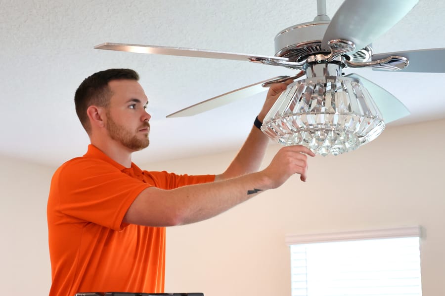 Mac 5 electrician installing light in ceiling fan.