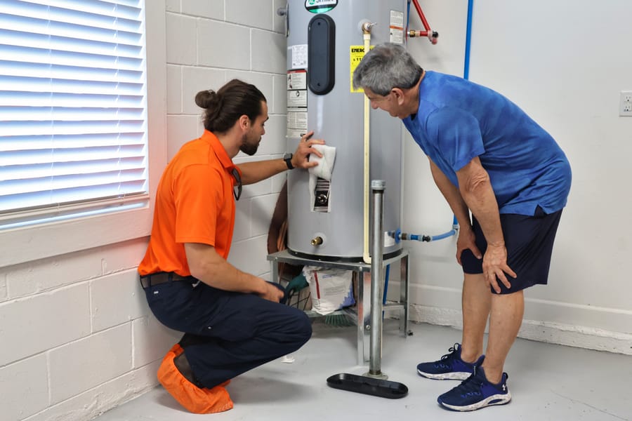 Plumber showing client a water heater during plumbing inspection.