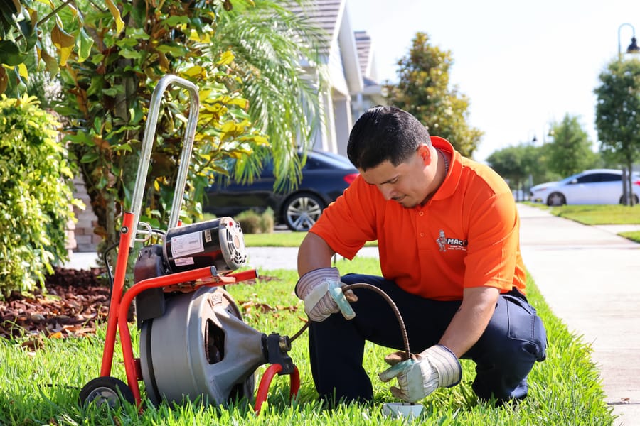 Mac 5 plumber conducting rooter service in yard.